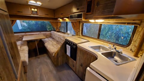 Kitchen and dining area with stove, oven, sink, and storage. Refrigerator across from sink.