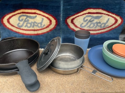 And here is your cookware - a deep cast iron skillet with a lid, a couple pots and pans, and some plates and bowls.
