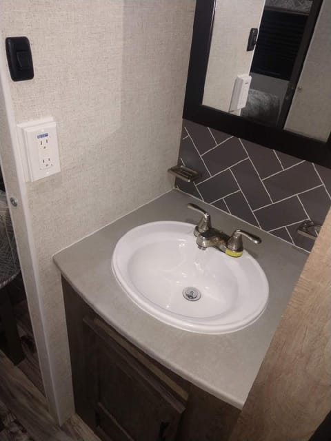 Sink is located outside of the restroom  in the hallway area.