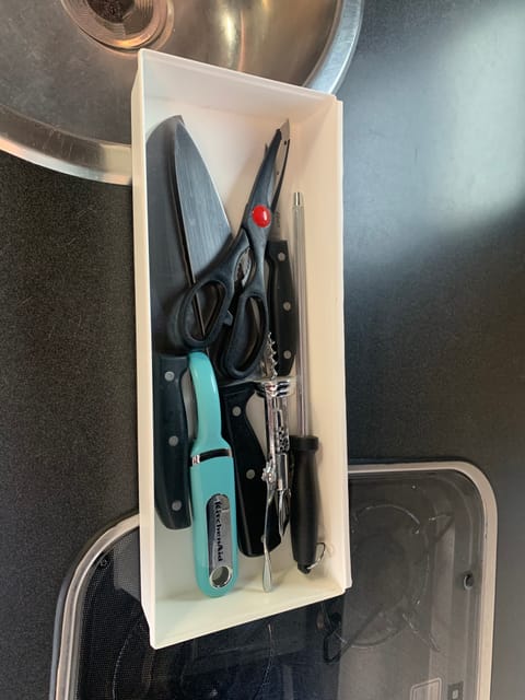 Knives, peeler, scissors, and corkscrew for meal prep.
