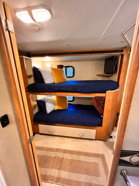 Twin bunks outfitted with Beddy's mink linens with storage drawer below. Both beds equipped with TVs for entertainment and slider windows 