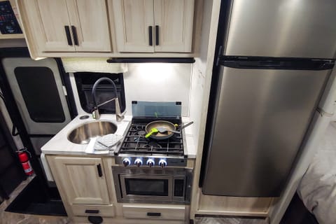 Kitchen with large fridge, stovetop, sink, and convection microwave oven