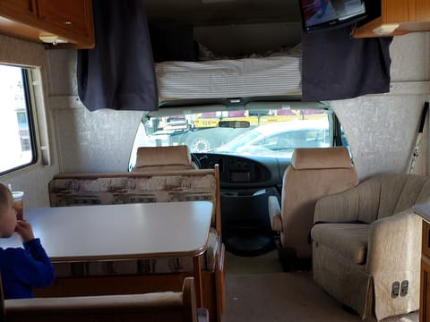 Shown: dinette (folds down into a bed), chair and cab, bed above cab with privacy curtains.