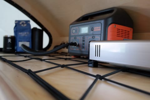 Rear interior view of our cargo net, Iwatani single-burner stove, and a (very helpful) Jackery 500W Power Station. 
*Jackery 500W Power Station included with any rental DoDrop ALPHA or DoDrop booking*