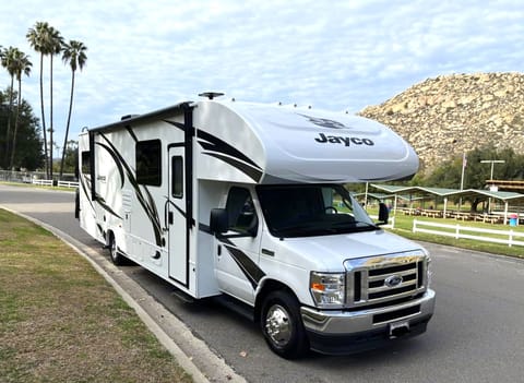 Discover the art of traveling with our 2022 Jayco Redhawk 31F, elegantly stationed on the curb with a picturesque landscape as its canvas. Beyond the wheels lies a world of endless possibilities, where time slows down and nature's grandeur takes center stage. The carefully manicured garden and scenic backdrop beckon you to savor the moment, to breathe in the fresh air, and to relish the freedom of the open road. As the 2022 Jayco Redhawk 31F stands ready to carry you to the next chapter of your journey, the harmonious blend of architecture and nature reminds us that every step we take brings us closer to the heart of discovery, making this rental experience one filled with emotion, wonder, and boundless beauty.