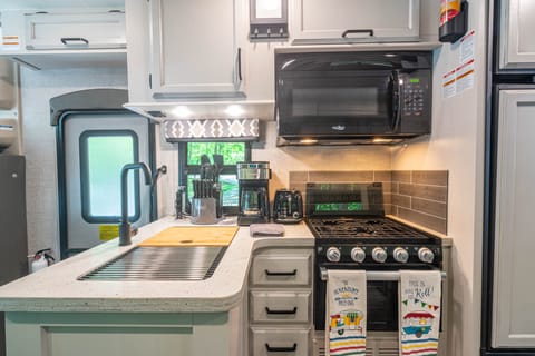 The kitchen area includes appliances, good counter space, a double sink, and cute decor.  For safety, a fire suppressant is mounted above the stove.