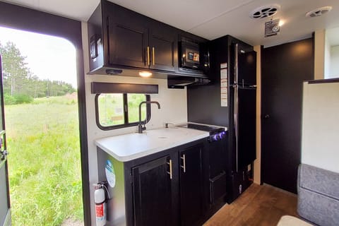 Kitchen with cooktop, sink, microwave, and fridge