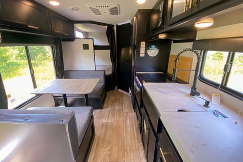 Interior image showing booth dinette, cooktop, oven, kitchen sink, and double bunks