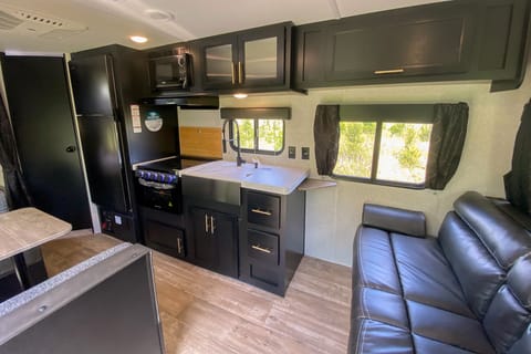 Interior image showing cooktop, oven, kitchen sink, fridge, and couch