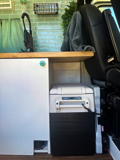 Powered fridge with camp stove stored next to it.