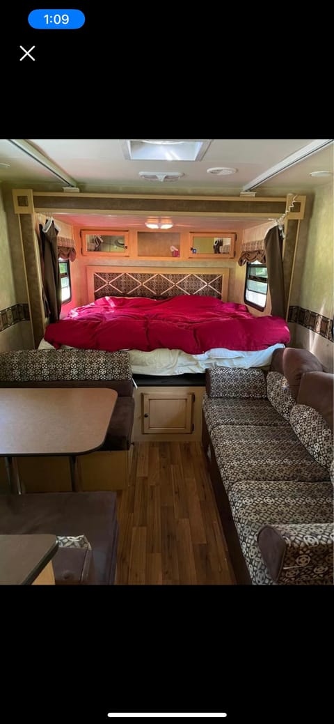 Dining table, couch, and the king size bed behind, with curtains to close for privacy. 