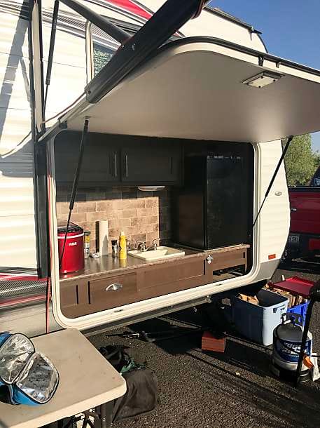 Outdoor kitchen with propane grill, sink, storage, and mini-refridgerator.