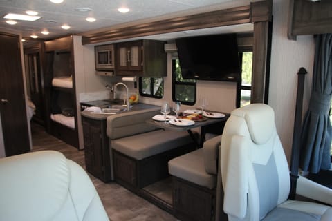 Living space offers pull out 68" sofa, a booth dinette with seating for four, 36” LED Television, a drop down bunk above the cab, plenty of storage.