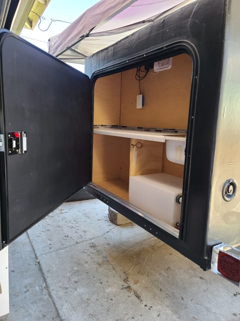 Rear kitchen with countertop, electric outlets, sink, water tank (NOT POTABLE WATER NOT FOR DRINKING), and room for portable refrigerator or cooler. 