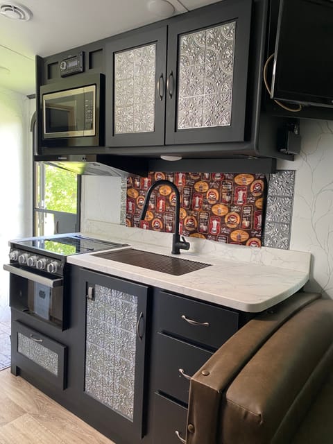 Kitchen showing front door, microwave,
3 burner gas range and 17" Furrion stove, sink, cabinets and window.