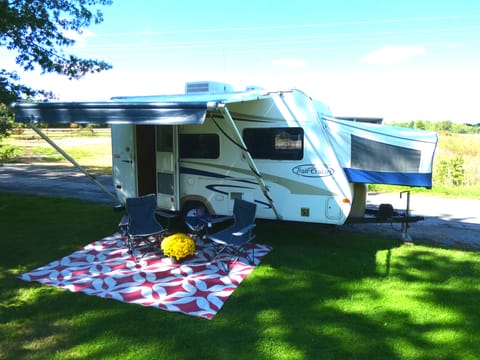 Setup with awning, outdoor carpet and folding camping chairs.