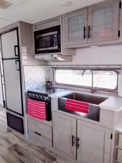 Gas stove, microwave, oversized refrigerator and sink.