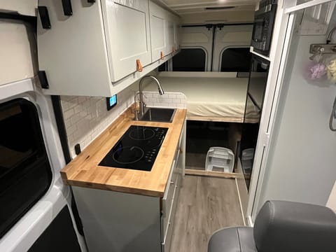 view of the galley kitchen and full size bed in back, as well as refrigerator and microwave on the right.