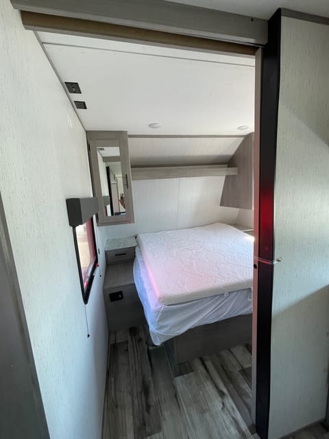 Bedroom with queen size bed, storage behind mirrors and underneath bed.  