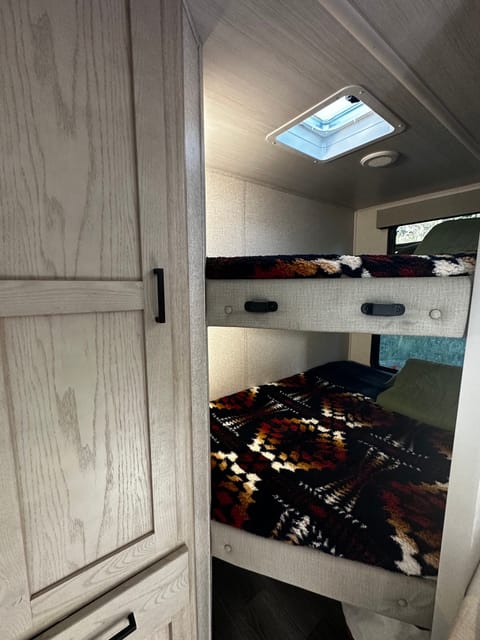 Full size double bunks are in the back, both have windows and the upper bunk has a skylight vent. Wardrobe and large storage underneath