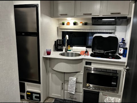 big fridge with freezer, deep sink, storage above and below.  Utensils galore, 2 burner gas stove with glass top.