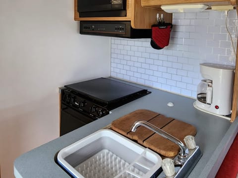 The kitchen has a gas range and oven with a microwave mounted above. The fridge is across the walkway. All the kitchen essentials are provided.