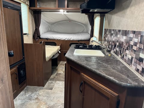 Kitchen area with sink, fridge, stove and microwave. 