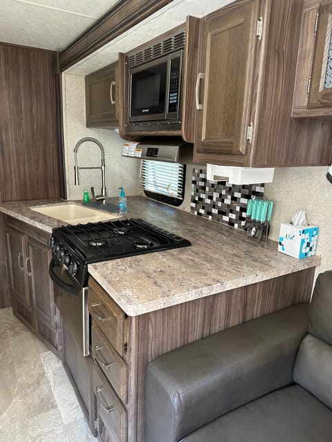 Three burner stove with drop in sink. The microwave is above the stove top and on each side is additional storage!