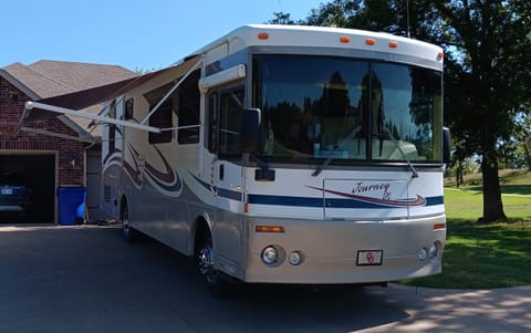 35' Winnebago Journey DL with awnings over the entrance door, patio area,  and master bedroom window.