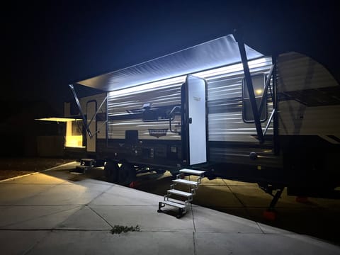 12ft exterior awning with strip lighting. outdoor kitchen with fridge and small kitchen sink. 