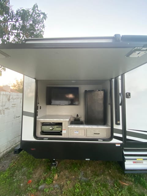 Large outside kitchen with flat top grill, Large Refrigerator, Sink, and TV. For those nice nights outside 