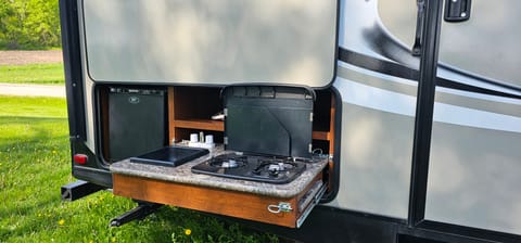 Outdoor kitchen with sink, small frig and stove.