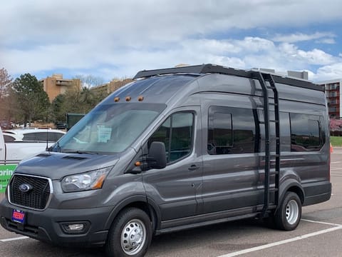 A 2023 model Ford Transit exterior with awning feature on the passenger's side.