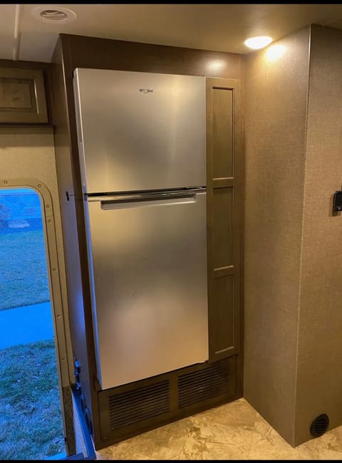 Residential size refrigerator powered by solar panels and long pantry cabinet to right