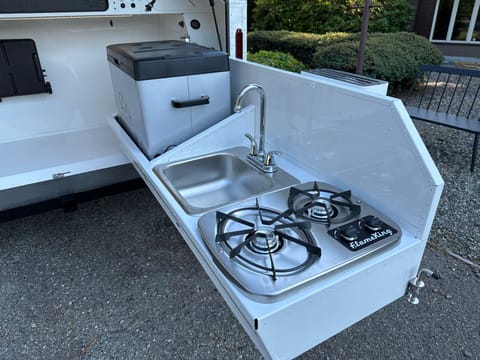 Two burner stove that works off propane, kitchen sink works off 28 gallon on board cold and hot water. Also includes chest style refrigerator/freezer
