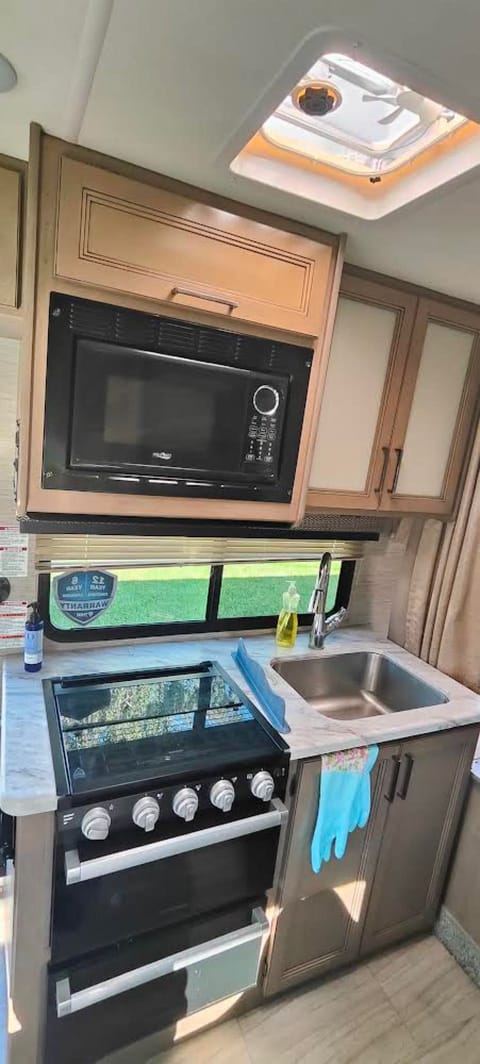 Kitchenette with a deep sink, small microwave, oven, and a Keurig single-serve coffee maker (not shown in picture but available in RV)