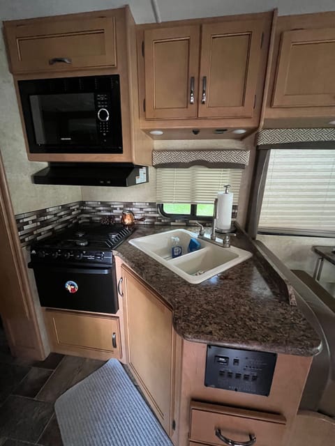 Double sink, stove top, oven and microwave, trash can under the sink and storage all around. 