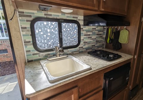 Kitchen has a large sink with upgraded pull-out sprayer faucet, a 2-burner propane stove, and a microwave-convection oven. 