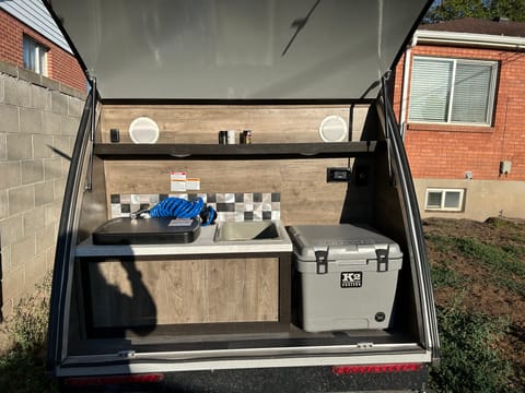 Galley kitchen area. Sink. Two burner propane stove. Insulated cooler. 