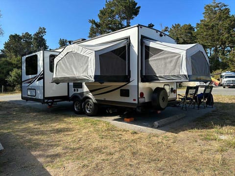 The back of the camper, its slide out dinette, and two of the three queen size beds folded out.