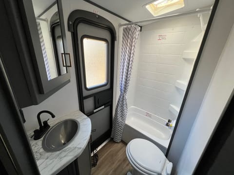 Bathroom located at rear of camper. Includes separate exterior door, toilet, shower, small tub only suitable for small children, sink, storage cabinet