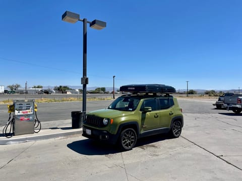 Jeep with closed Roofnest tent at gas station. 