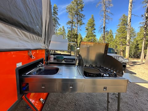 Outdoor kitchen w/ 4 burner gas stove, sink, running water, prep area, drawers for utensils, and lightning.  KITCHENWARE INCLUDED