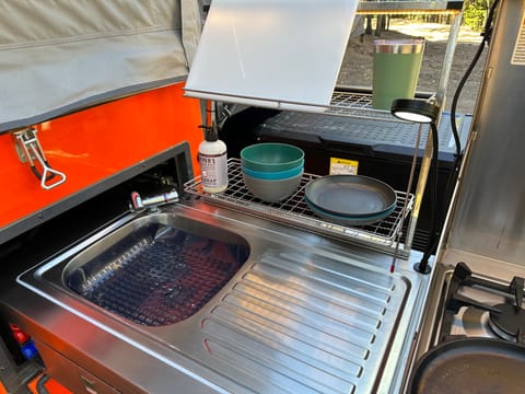 Outdoor kitchen w/ 4 burner gas stove, sink, running water, prep area, drawers for utensils, and lightning.  KITCHENWARE INCLUDED
