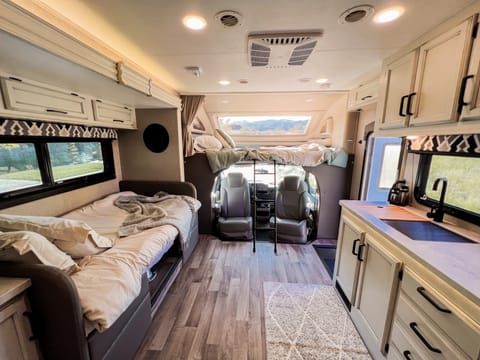 The dinette doubles as a twin size bed and the loft bunk can fit 2 adults. You can also see the driver and passenger chairs swivel to face the dining area for extra seating. 