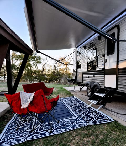 Dusk under the awning. Camping loveseats and outdoor rug. Table top grill.