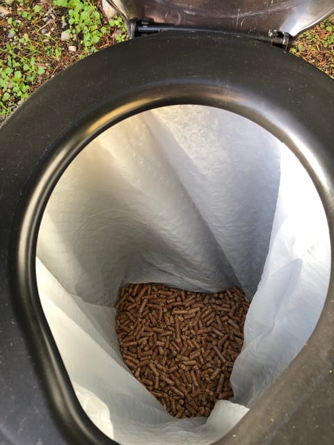 The toilet is lined with a garbage bag and wood pellets are placed in the bottom to absorb liquids.  