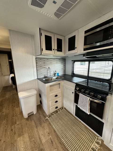 Kitchen area has a refrigerator and freezer, 3 burner gas stove, small gas oven, and a microwave.