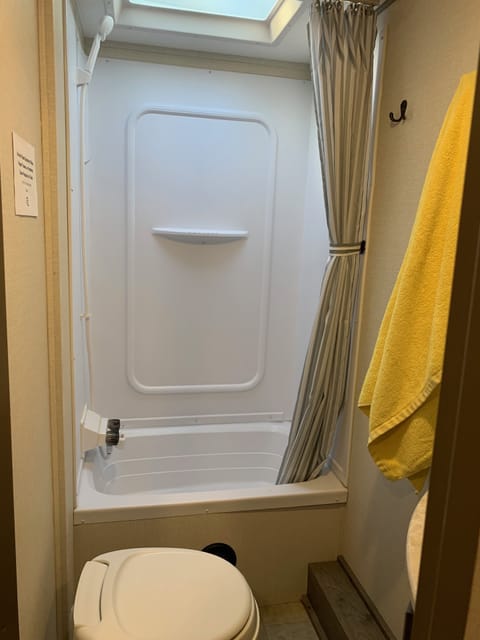 One of the great perks of the camper is the bathroom.  Enjoy a hot shower to get your morning going, or wash off the day.  The bathroom features a tub and shower, with a skylight overhead.  A motorized fan and vent to help bring cool air in and get the steam out.  A commode, sink and faucet and cabinets with adquate space for storage complete the bathroom.