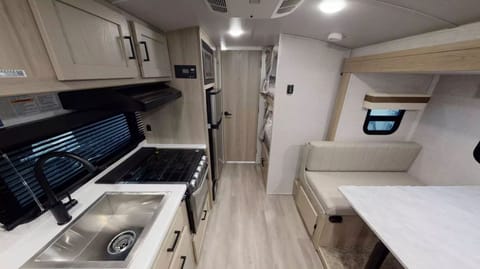 Picture of the inside of the Geo Pro RV Trailer. Dinnete, Kitchen, part of the bunk beds and bathroom door
